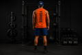 Forged Core Training Tank — back view, orange tank with FORGED branding in dark gym